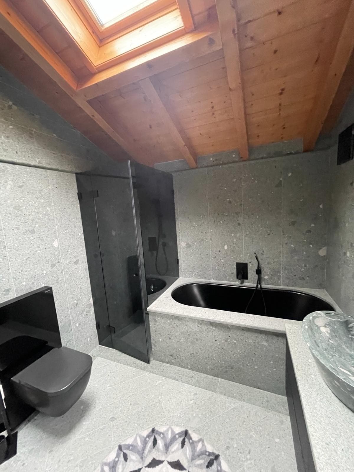 Salle d'eau en béton ciré avec douche en verre et lavabo noir encastré, rénovation DEN Sanitaire