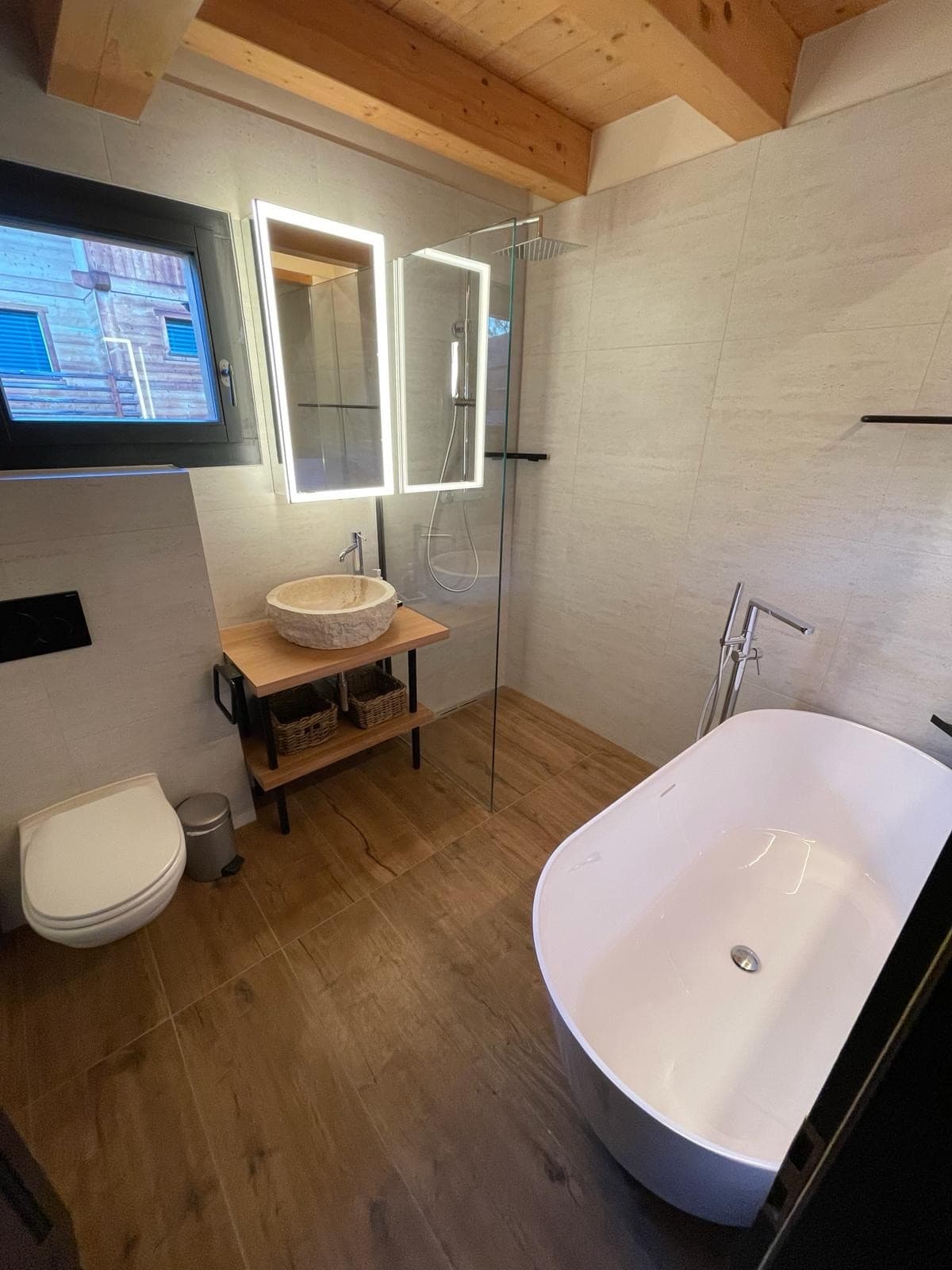 Lavabo sur pied en pierre naturelle et douche en verre, salle d'eau rustique moderne à Verbier